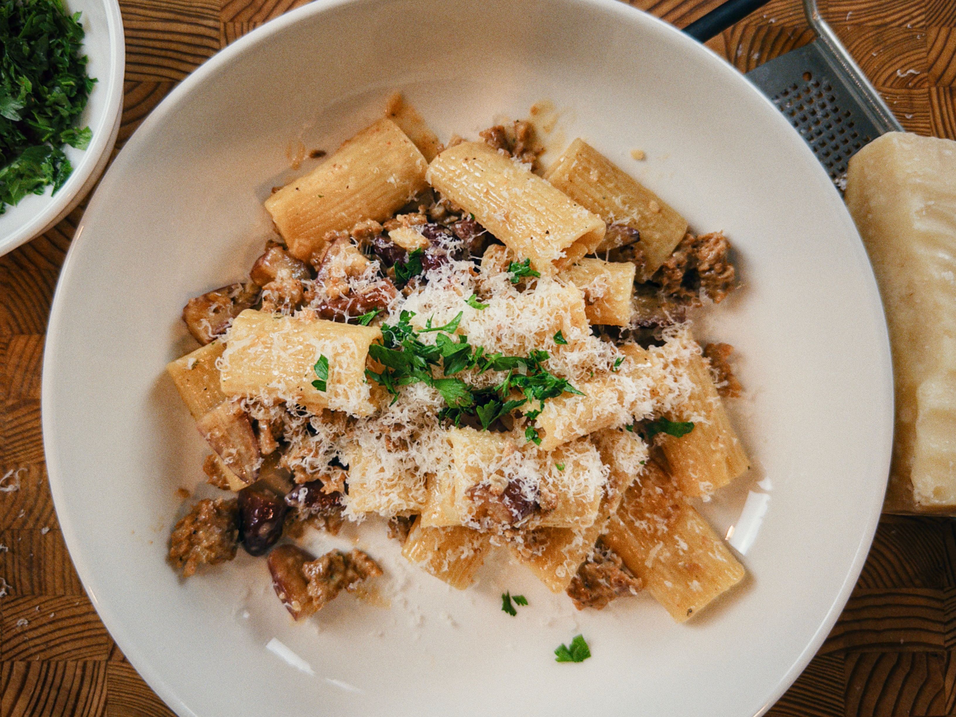 Rigatoni cremoso com linguiça dourada, pinhão picado, parmesão e salsinha.