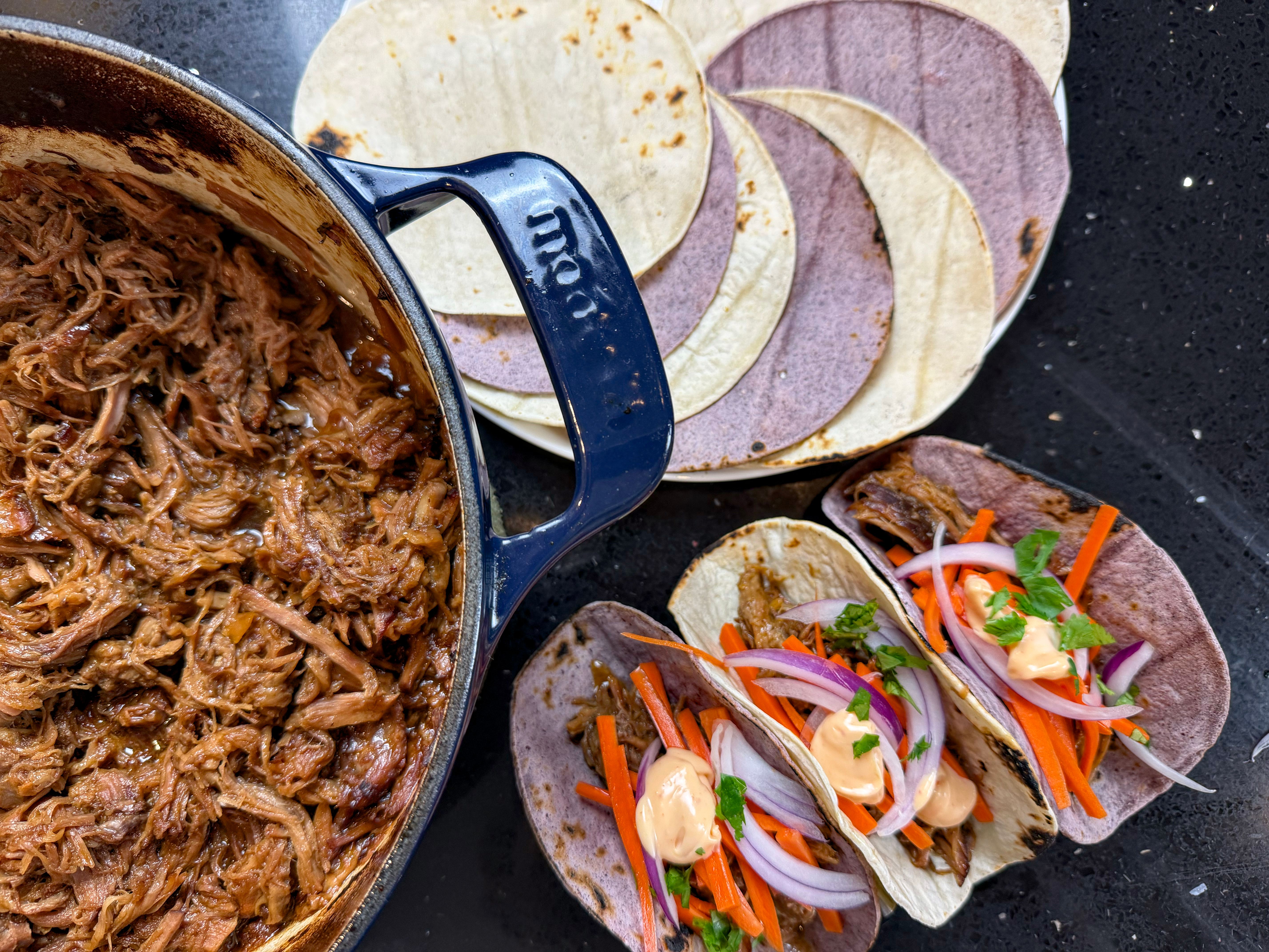 Carne de porco desfiada ao molho asiático servida em tortillas com cenoura fatiada, cebola-roxa, coentro e molho